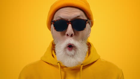 Cheerful-elderly-man-goofing-in-studio.-Mature-guy-showing-tongue-indoors.