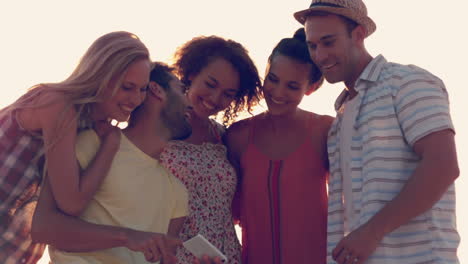 group of happy friends watching photos on smartphone