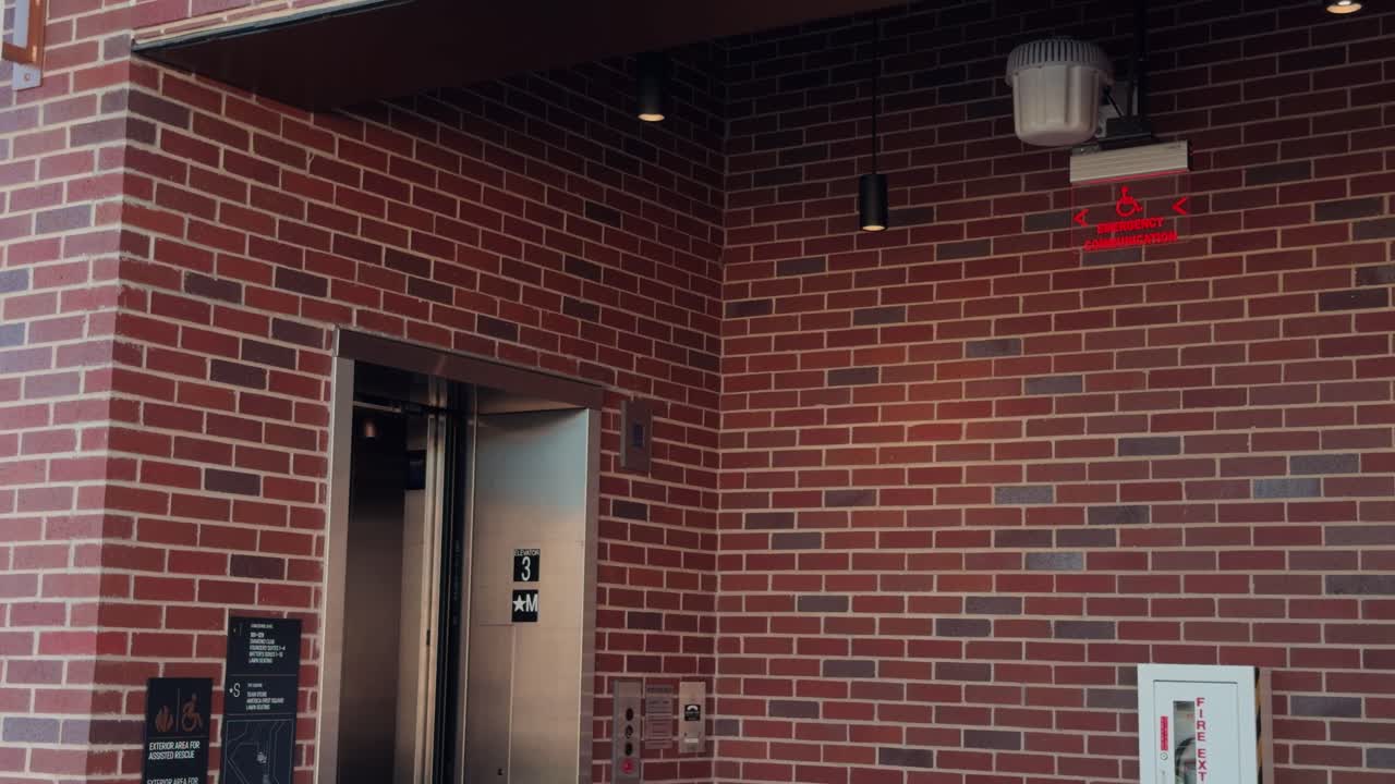 Static real time shot of elevator doors opening, pausing, and closing on brick wall