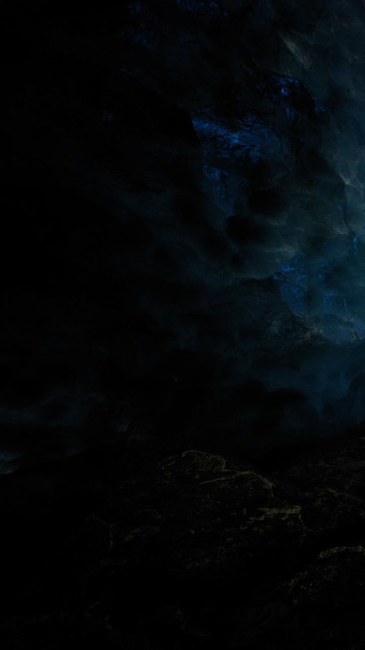 Night scene of a cave with mysterious blue light shining in darkness