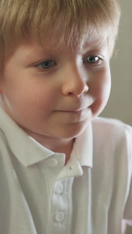 cute toddler boy looking at laptop screen with interest. child watches cartoons sitting in light cozy room. preschooler spends free time at home closeup