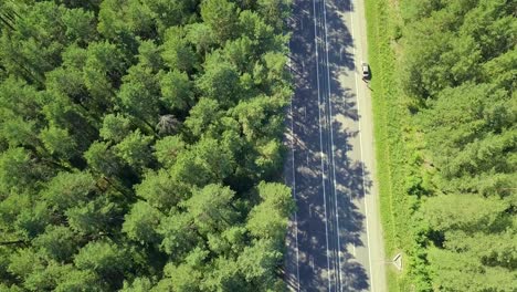 Vuelo-Aéreo-Sobre-La-Carretera-Que-Pasa-Por-Automóviles-Y-Camiones-En-El-Bosque-Y-El-Automóvil-También-Está-Estacionado-Al-Costado-De-La-Carretera