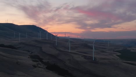 beautiful aerial landscape view of wind turbines on a windy hill during a colorful sunrise