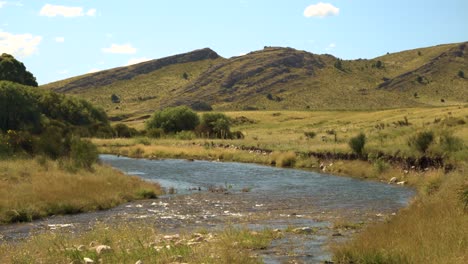 magnífica vista de las montañas a lo largo de las orillas del río y de los exuberantes campos verdes durante el día: plano general