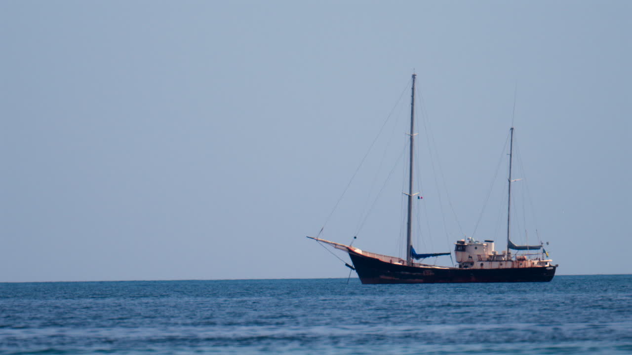 Distant view of a rusty boat moving on the sea in the south of France, on a cloudy day
