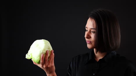 young woman holding and looking at cabbage, vegan and healthy diet concept