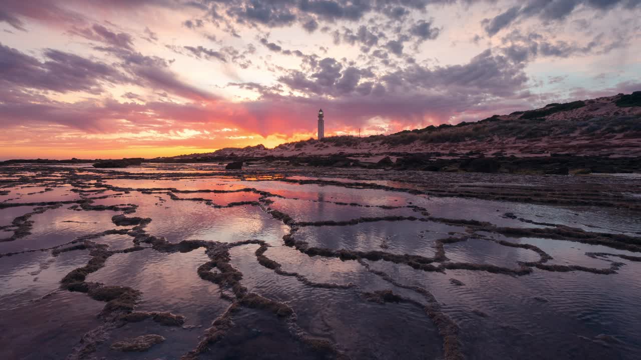 inclinar hacia arriba hermoso time-lapse puesta de sol en el faro de trafalgar con patrón rocoso en primer plano y pequeños estanques de agua