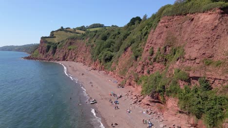 aerial drone side shot of ness cove beach with many tourists relaxing during beautiful summertime