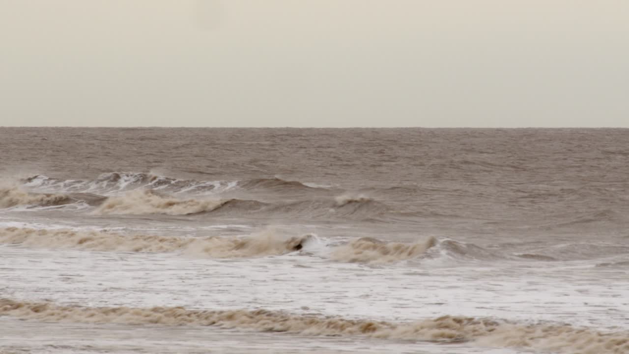 추운 암울한 겨울 파도가 ingoldm musicells, skegness 모래 해변에 부 ⁇ 히고