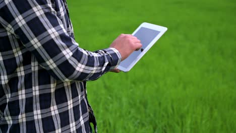 primer plano de un granjero que lee o analiza un informe en una tableta en un campo de agricultura verde. imágenes de alta calidad en 4k