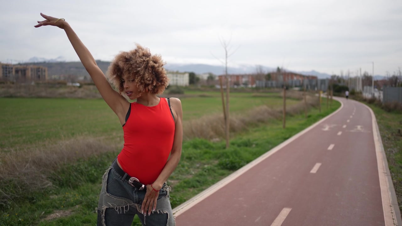 Uma jovem estilosa fazendo uma caminhada tranquila em um caminho ao ar livre, vestida com trajes casuais.