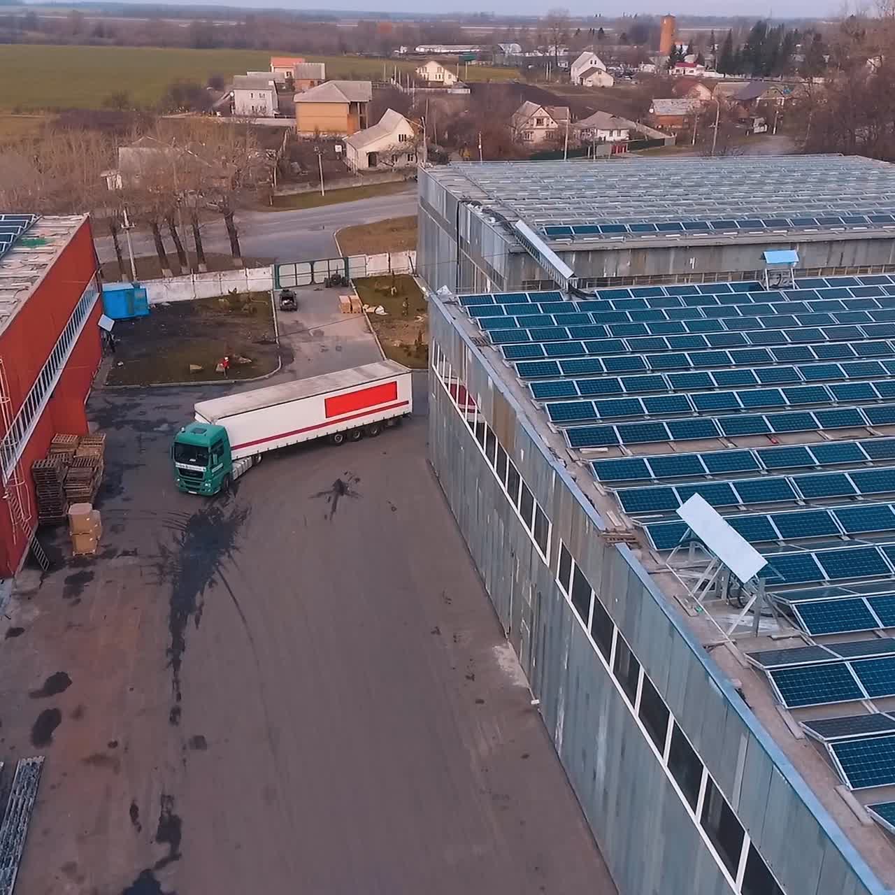 Aerial view on stock with solar panels on roof. Big truck is arriving to territory. Factory or plant. Green energy. Video