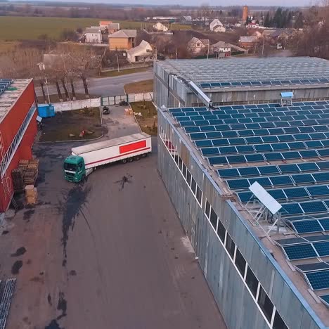 aerial view on stock with solar panels on roof. big truck is arriving to territory. factory or plant. green energy. video