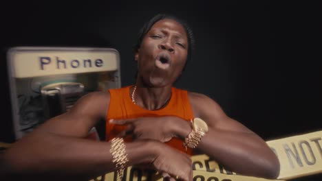 black musician rapping at crime scene with street payphone and caution tape