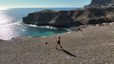 young woman with long hair walks near the cliff and where you can see the beautiful beach of medio almud on the island of gran canaria and on a sunny day