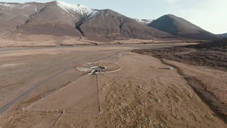 Slow-dolly-shot-towards-old-icelandic-sheepfold,-mountain-landscape