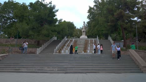 people walking up and down stone steps with fountains and monument in a park