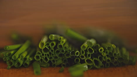 macro shot of a male hand cutting fresh chives on a wooden board