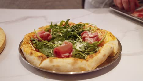 chef adds meat on top of freshly baked pizza