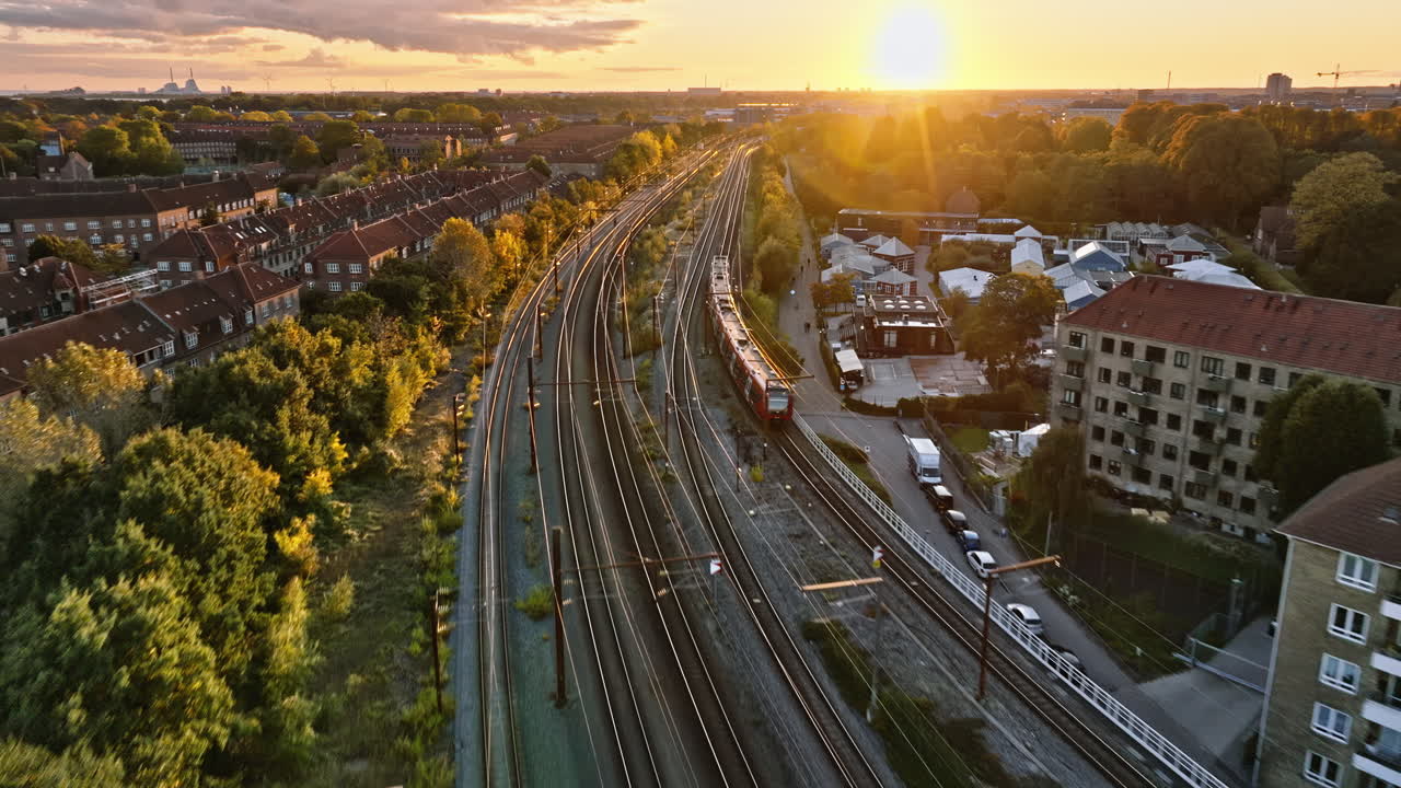 Aerial drone view of a train moving on the tracks near Vesterbro district in Copenhagen, Denmark at sunset