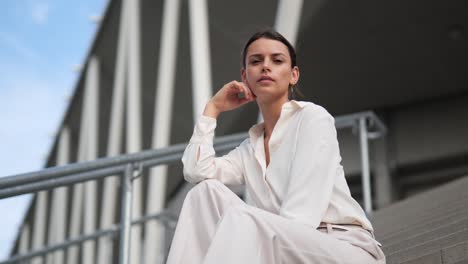 a businesswoman sitting on stairs and turning her head towards the camera