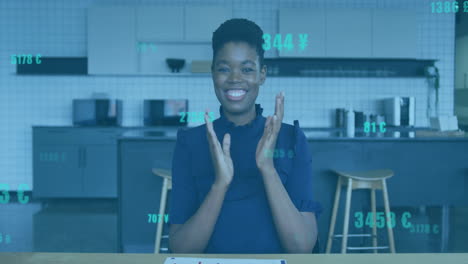 woman clapping hands in break area, finance numbers and currency icons floating around wooden table