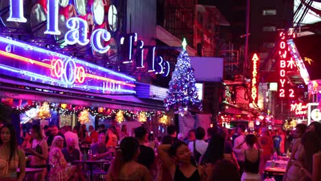 crowded street with neon lights and christmas tree