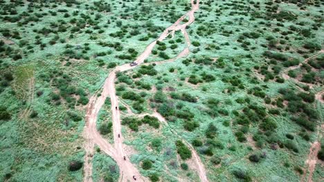 Caravana-De-Safari-Con-Motocicletas-Y-Jeep-Que-Viajan-A-Través-Del-Paisaje-De-Kenia---Panorámica-Aérea