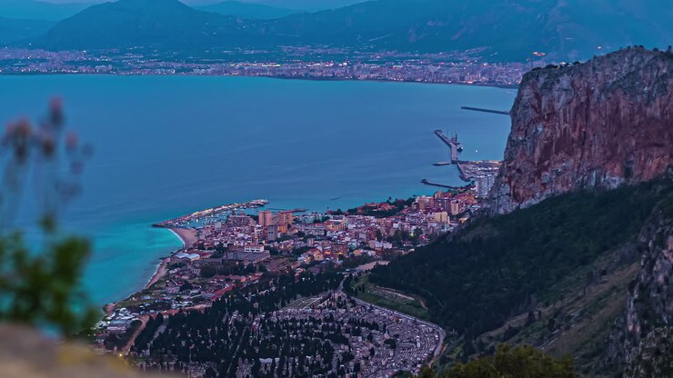 Vista em time-lapse de uma cidade costeira do dia para a noite com luzes brilhantes da cidade