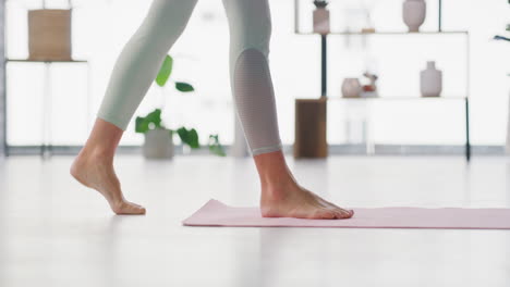 a woman rolls out a yoga mat on the floor