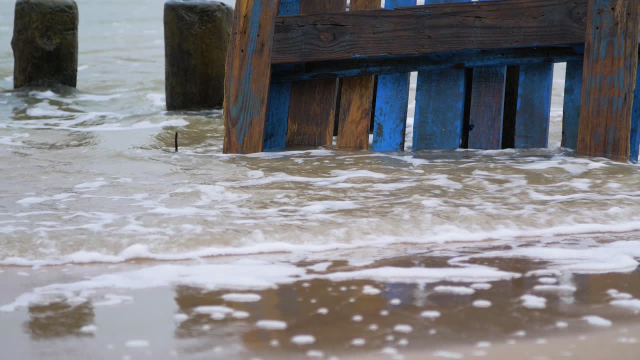 Old blue wooden EPAL palette on the shore, trash and waste litter on an empty Baltic sea white sand beach, environmental pollution problem, overcast day, closeup shot