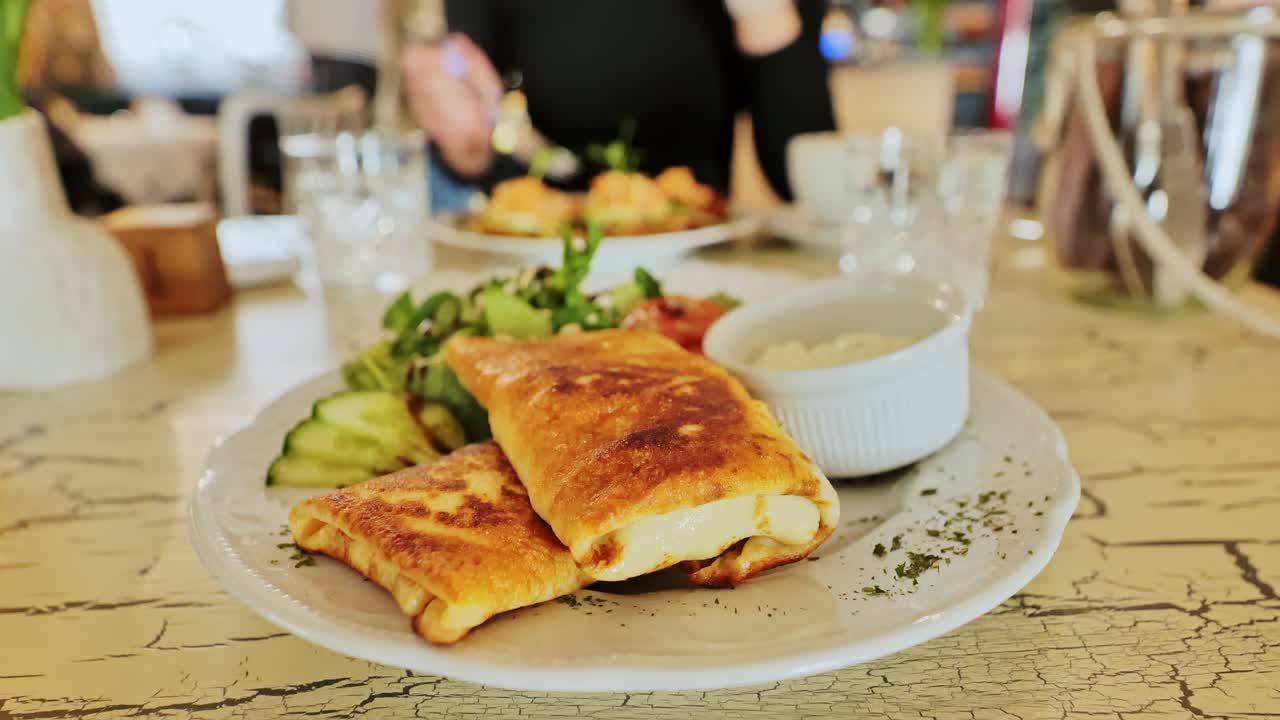 Delicious crepes with ham, cheese plated with salad and dip, cozy cafe setting