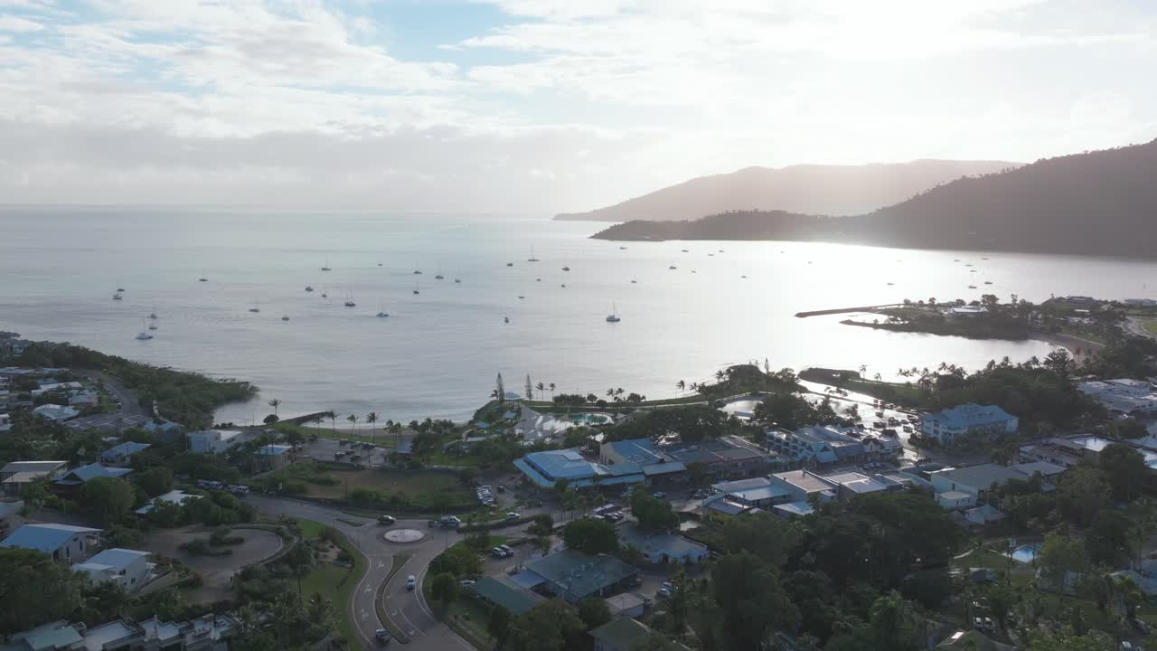 Port Airlie Beach Bay Lagoon gateway Great Barrier Reef Whitsundays Whitehaven aerial drone sunrise morning mist sunny coastline marina jetty sailboats Coral Sea Marina backwards slowly motion