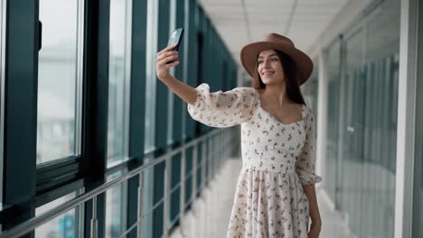 hermosa chica alegre en una tabla y un sombrero hace un selfie en un teléfono inteligente