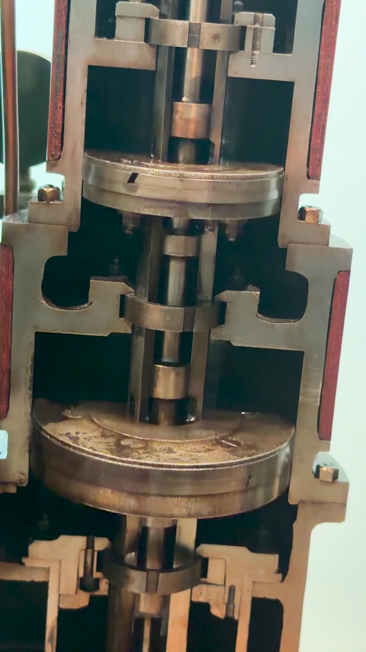 Detailní záběr na průřezový model průmyslového parního stroje demonstrující vnitřní mechanický pohyb pístu.