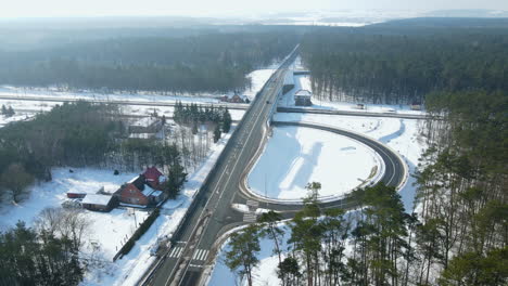 El-Coche-Viaja-Por-El-Puente-Elevado-Con-Bosque-Y-Carretera-Curva-Durante-La-Temporada-De-Invierno-En-Rakowice,-Cracovia,-Polonia