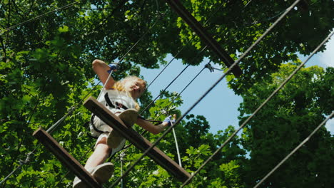 a brave child walks along a tightrope between tall trees active childhood and fun