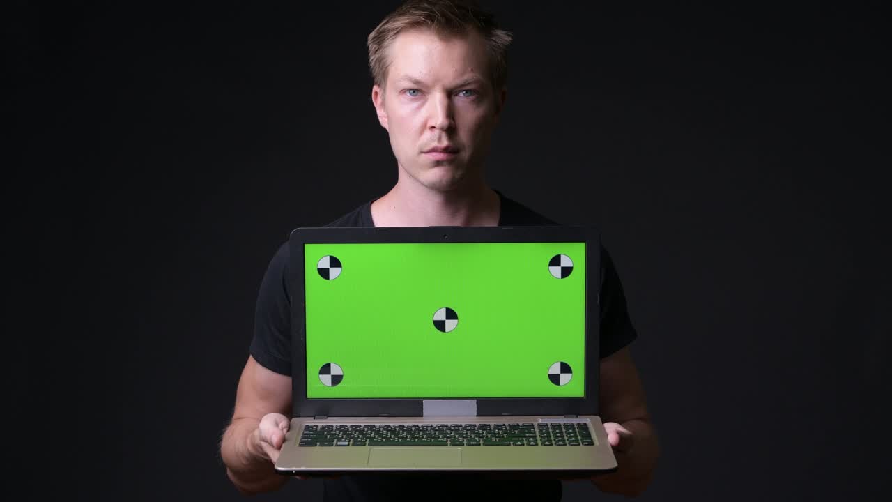 hombre sosteniendo una computadora portátil con pantalla verde de clave de croma