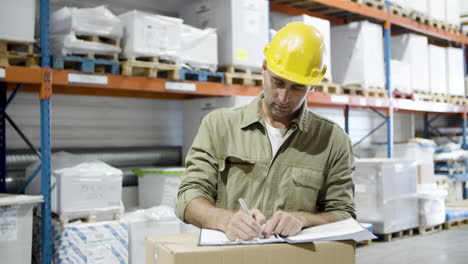 focused caucasian worker signing documents in warehouse