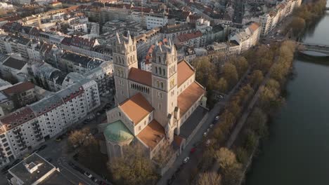 Drone-Aéreo-De-5k-Sobre-La-Azotea-De-La-Iglesia-De-San-Maximiliano-Y-El-Río-Isar-Con-El-Paisaje-Urbano-De-Munich,-Alemania