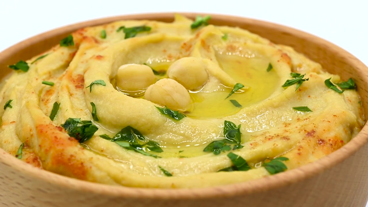 Ciotola di hummus di ceci in rotazione su sfondo bianco