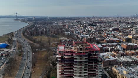 a high angle view above a new high-rise construction site, with shore parkway and the verrazano bridge in view