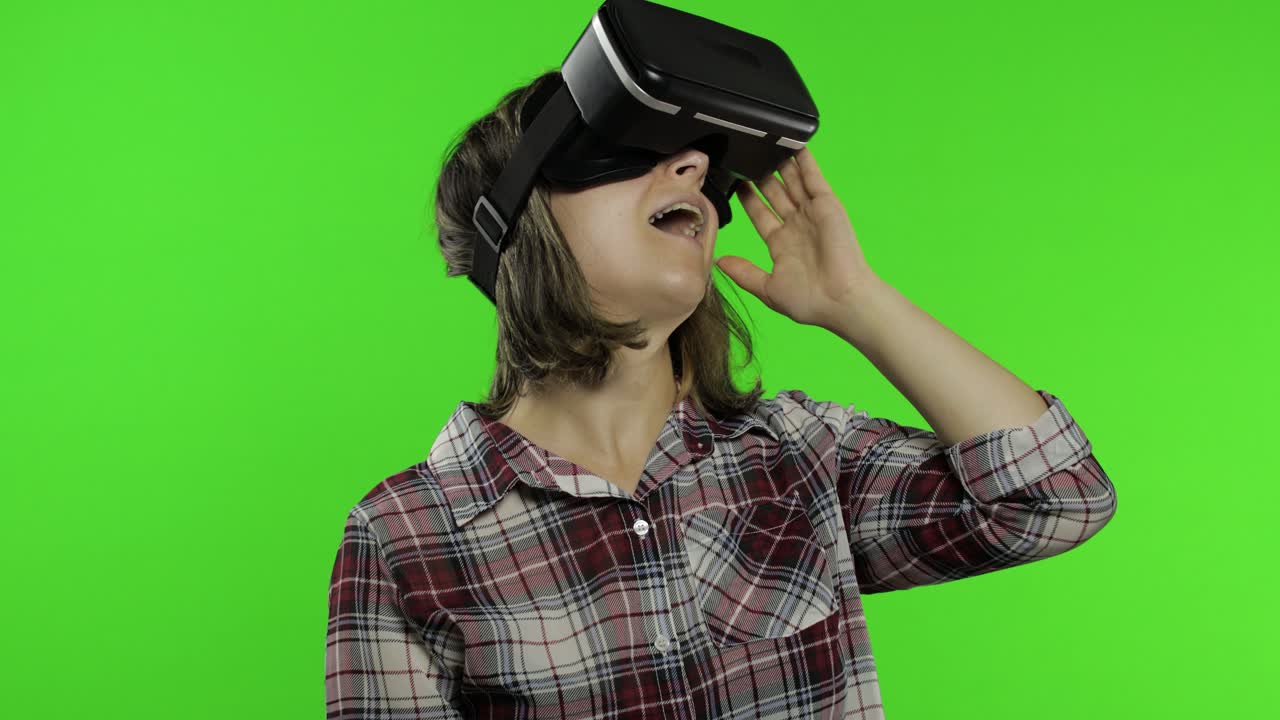 Young girl using VR app helmet to play simulation game. Woman watching virtual reality 3d video