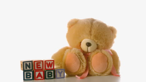 cute teddy bear falling besides baby blocks