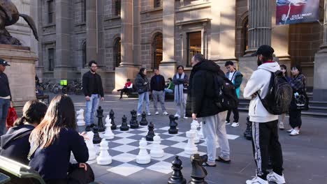 people playing and watching a giant chess game