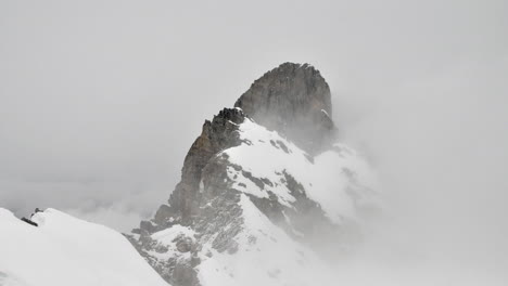 time lapse of cloud rolling around a snow covered mountain peak in the french alps in winter