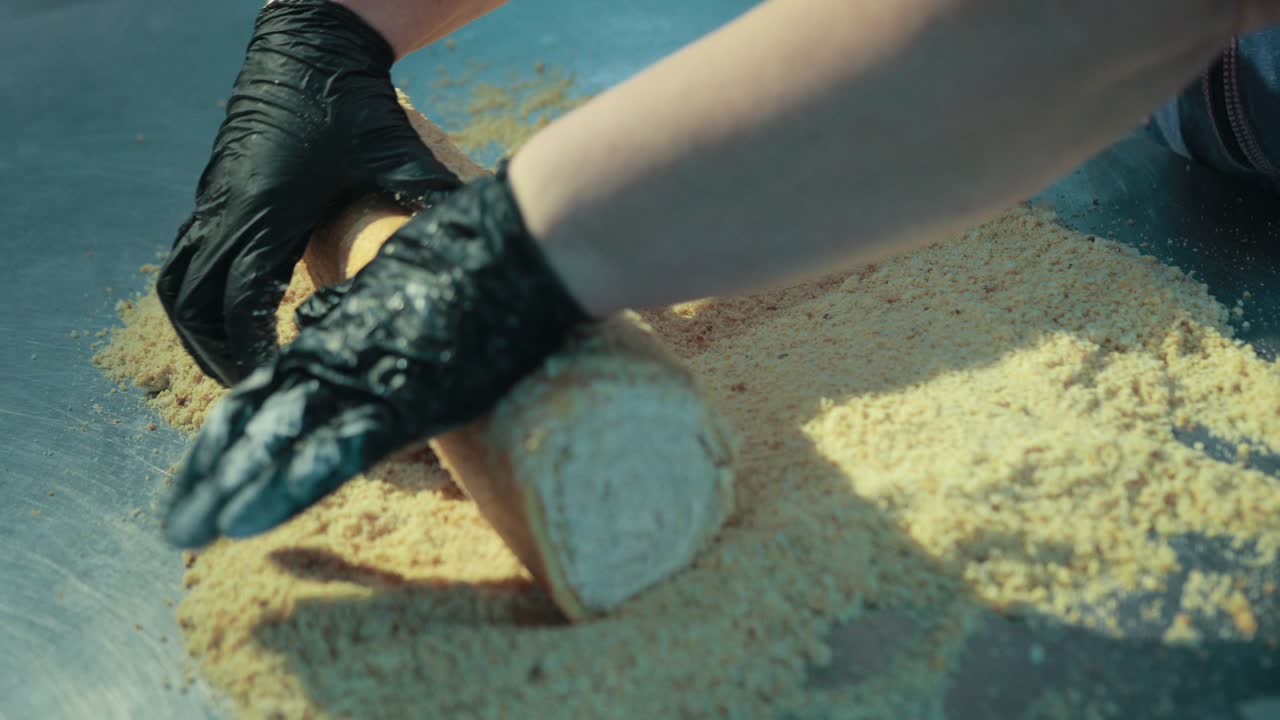 여성 베이커는 은 견과류로 크림 스폰지 케이크를 장식하고 있습니다.