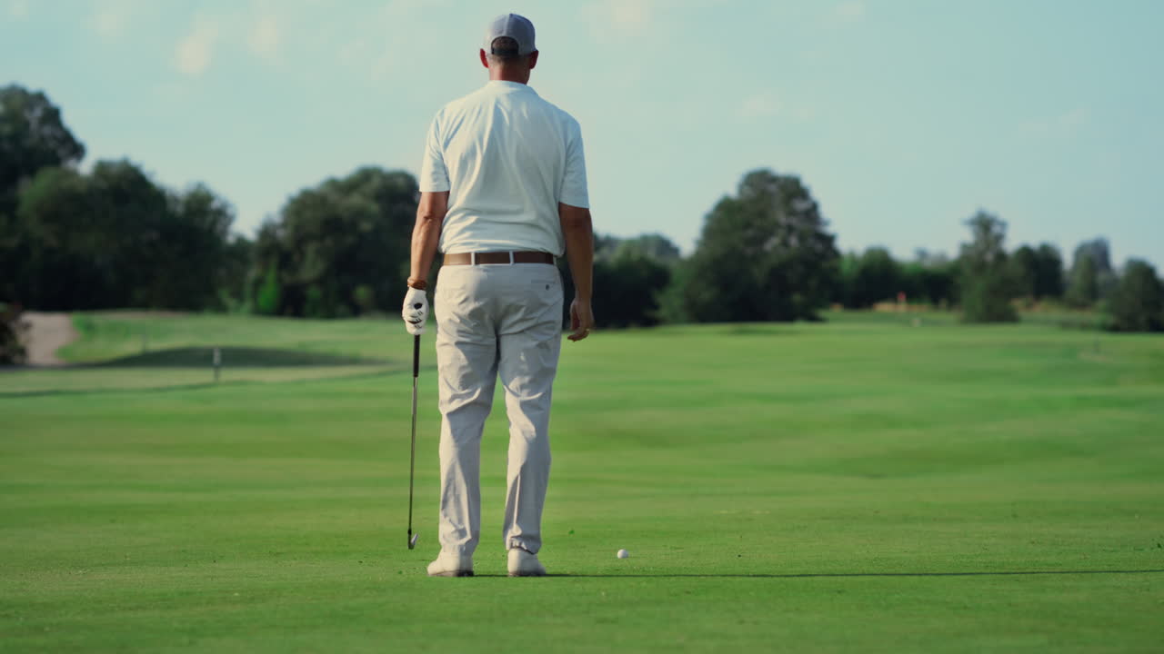 Uomo in piedi da solo su un campo da golf all'aperto. Un giocatore si gode l'aria fresca in estate.