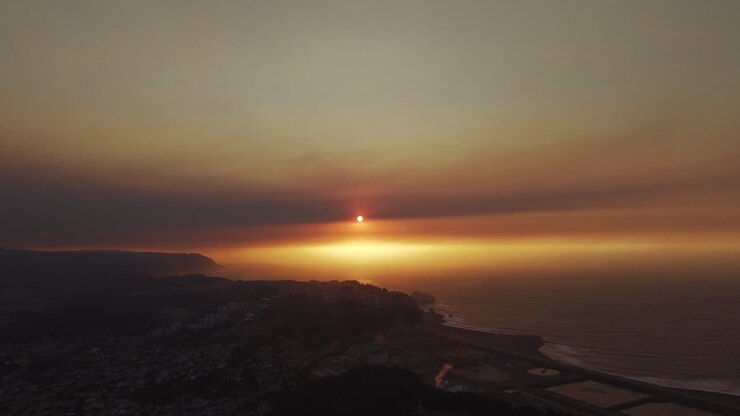 Splendido panorama aereo all'ora d'oro di un tramonto sull'Oceano Pacifico, con la città di Constitución avvolta in un caldo alone di foschia