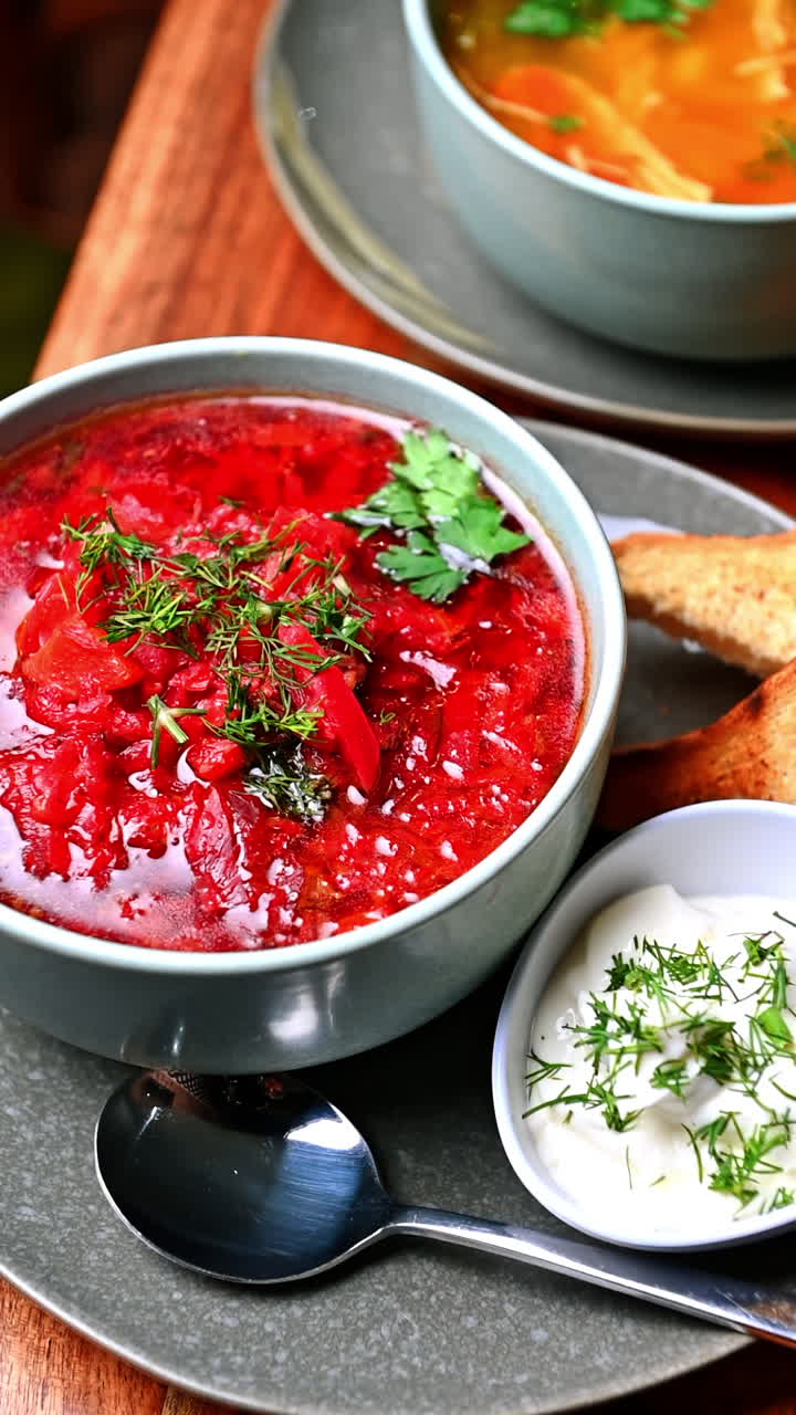 Traditional red borscht soup with sour cream and herbs. Close-up of homemade Ukrainian red borscht served in ceramic bowl with sour cream and dill on wooden table